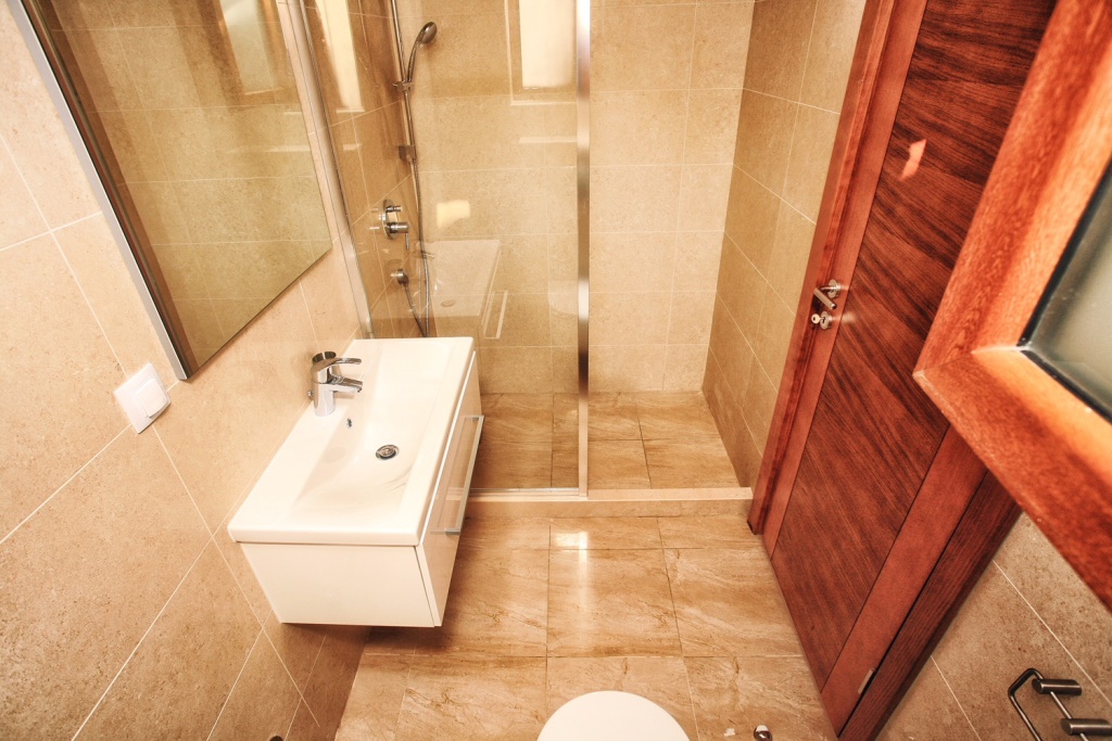 Modern bathroom with a shower cabin in a villa in Herceg Novi, Montenegro: white sanitary ware and beige tiles.