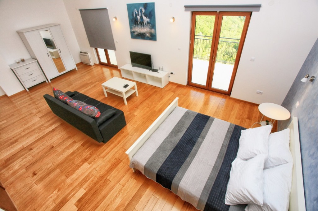 Bright bedroom with a double bed and seating area in a villa in Herceg Novi, Montenegro, mountain view from the window.