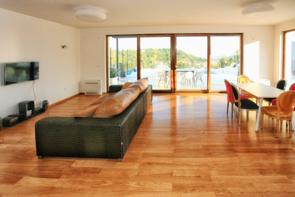 Spacious living room in a villa in Herceg Novi, Montenegro: leather sofa, dining area, and access to the pool on the terrace.