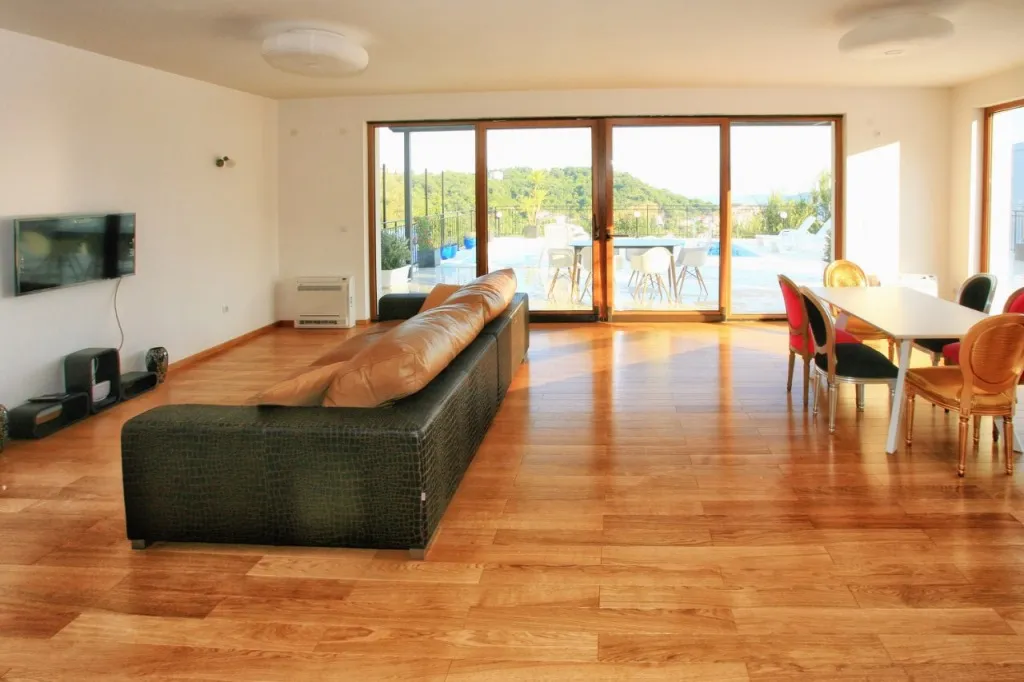 Living room with sofa, TV, and dining area on wooden flooring.