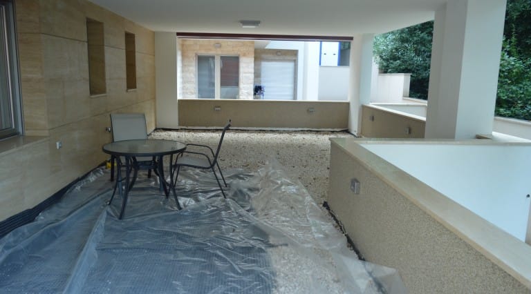 Spacious terrace with stone finishes and furniture in an apartment in Ljuta, Montenegro. View of the open balcony with gravel.