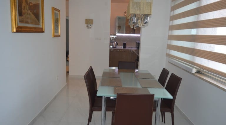 Dining area with a modern table and chairs in an apartment in Ljuta, Montenegro, view of the kitchen and bright interior.