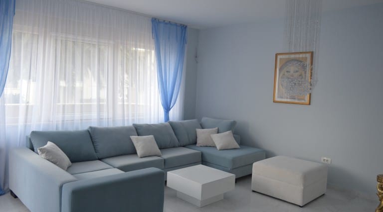 Bright living room in an apartment in Ljuta, Montenegro: corner sofa, white coffee table, and decor in blue tones.