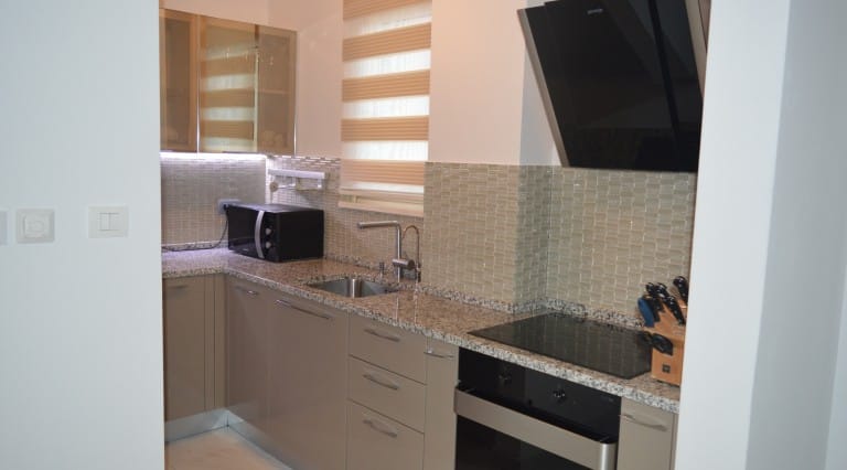 Modern kitchen in an apartment in Ljuta, Montenegro: granite countertop, built-in appliances, and stylish finishes.