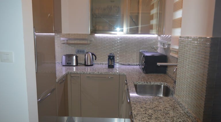 Modern kitchen in an apartment in Ljuta, Montenegro: glossy fronts, granite countertop, and built-in appliances.