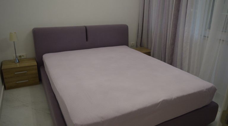 Cozy bedroom with a double bed in an apartment in Ljuta, Montenegro: modern furniture and a bright interior.
