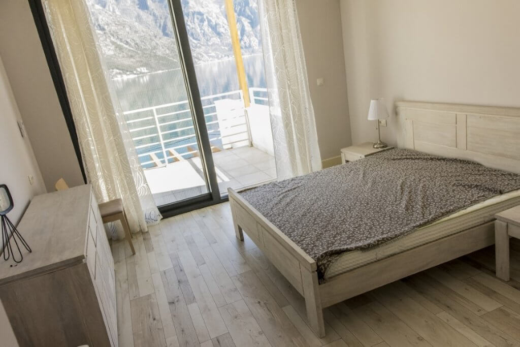 Bedroom with a double bed and a view of the sea and mountains in a villa in Stoliv, Montenegro, bright interior with panoramic windows