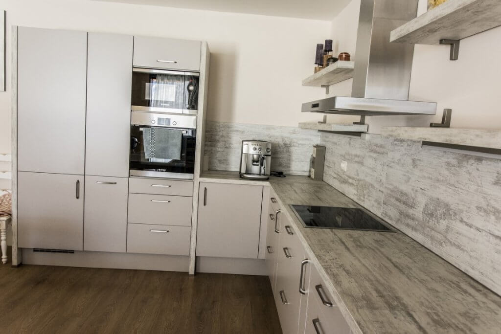 Modern kitchen with built-in appliances in a villa in Stoliv, Montenegro: light-colored cabinetry and wood-effect countertop.