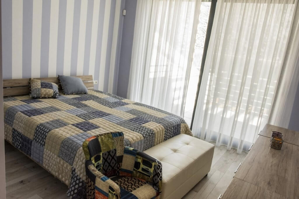 Cozy bedroom with a double bed and a panoramic window in a villa in Stoliv, Montenegro. Bright interior with furniture.