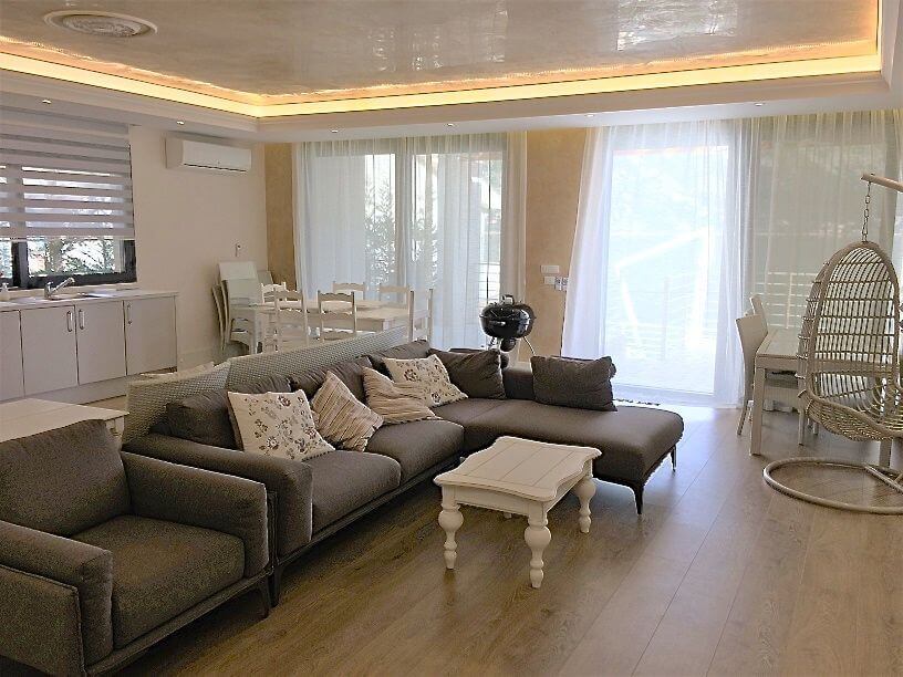 Living room in a villa in Stoliv, Montenegro: gray corner sofa, egg chair, dining area, and modern finishes.