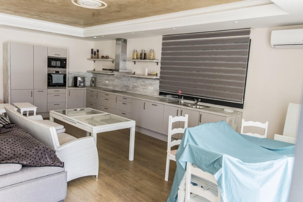 Modern kitchen-living room with white furniture and built-in appliances in a villa in Stoliv, Montenegro.