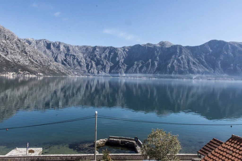 Panoramic view of the Bay of Kotor and the mountains from a villa in Stoliv, Montenegro: a seascape with the waterfront and pier.