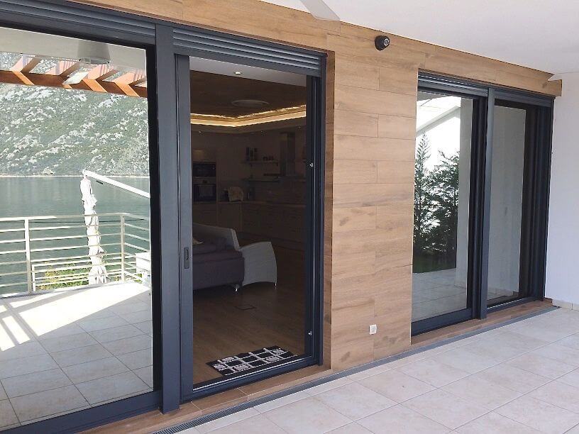 Villa terrace in Stoliv, Montenegro: panoramic windows, sea and mountain views, modern wood-style finish.