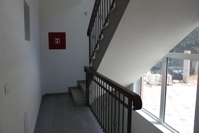 Stair landing with wrought-iron railings in a residential building in Dobra Voda, Montenegro: view of a bright entrance hall and window.