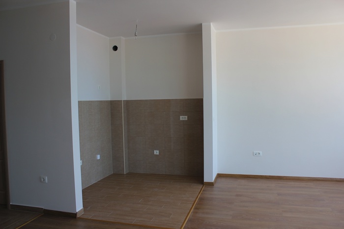 Kitchen area in a new apartment in Dobra Voda, Montenegro: light finishes, tiled backsplash, and laminate flooring.