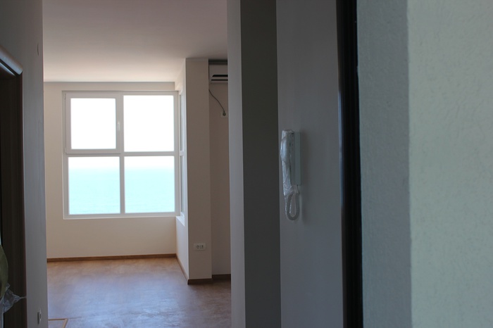 Bright living room with sea view in an apartment, Dobre Vode, Montenegro: panoramic window, air conditioner, and intercom.