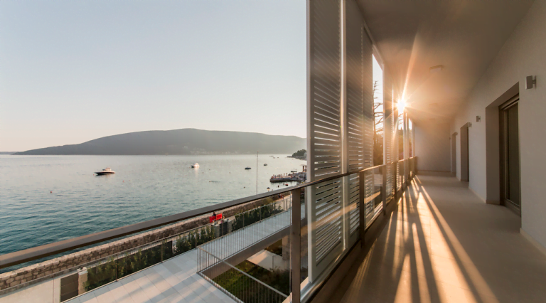 Spacious villa balcony in Herceg Novi, Montenegro, with panoramic views of the sea, yachts, and sunset lighting.