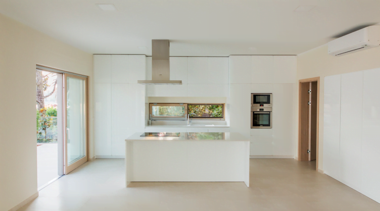 Modern white kitchen with an island and built-in appliances in a villa in Herceg Novi, Montenegro, with access to the terrace.