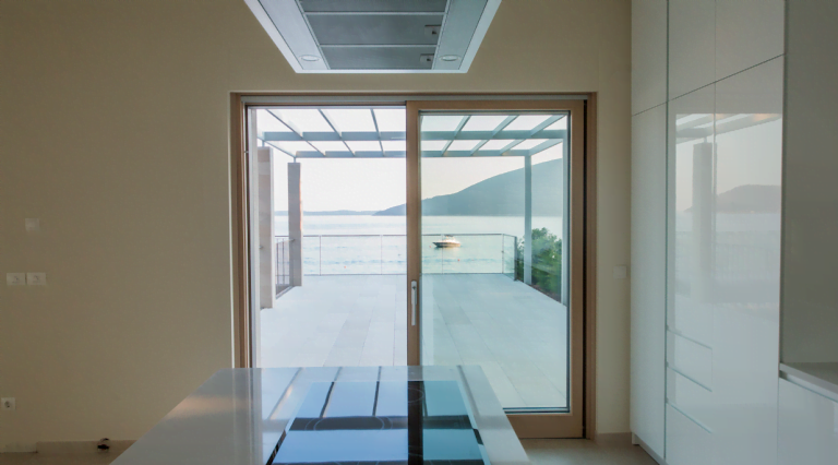 Modern kitchen with panoramic views of the sea and the villa terrace in Herceg Novi, Montenegro. White glossy cabinetry.