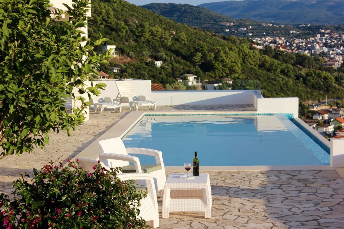 Swimming pool with a view of the mountains and the sea by the house in Dobra Voda, Montenegro: terrace with sun loungers and garden furniture.