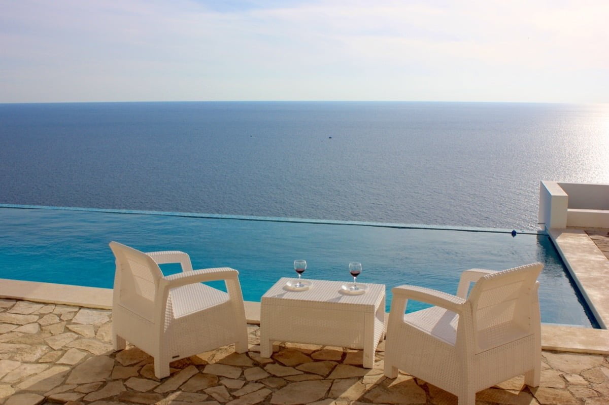 Terrace with an infinity pool and sea view in a house, Dobra Voda, Montenegro: white furniture and stone finish.