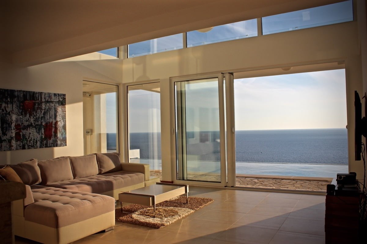Living room with panoramic windows and sea view in a house, Dobra Voda, Montenegro: modern furniture and a terrace with a pool.