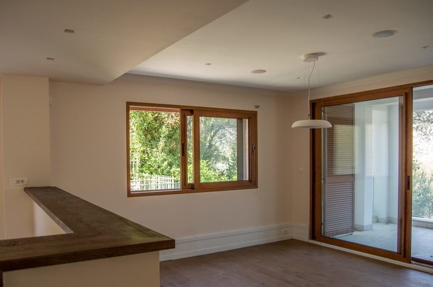 Empty room with wood flooring, window, and sliding glass door to balcony. Part of a wooden counter visible.