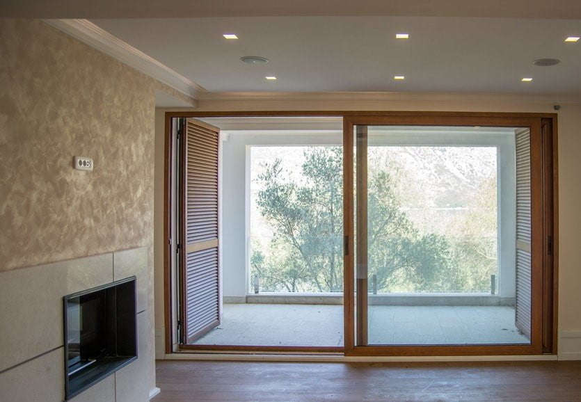 Living room with a fireplace and panoramic doors to the terrace in a villa, Stoliv, Montenegro: modern finishes and a view of the garden.