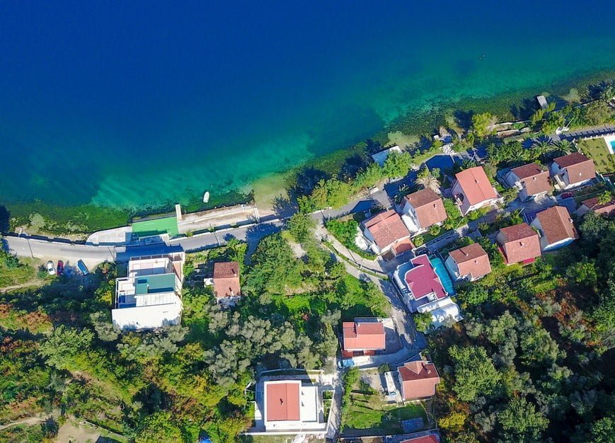 Aerial view of villas in Stoliv, Montenegro: coastal houses with red roofs by the clear Adriatic Sea.