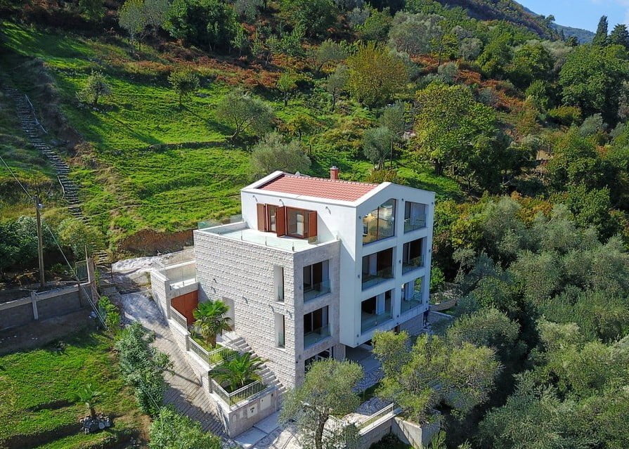 Modern villa with panoramic windows and stone cladding surrounded by greenery, Stoliv, Montenegro.