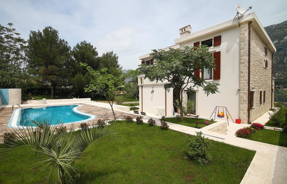 Two-story villa in Prčanj, Montenegro, with a private pool, a well-maintained garden, and a stone facade finish.