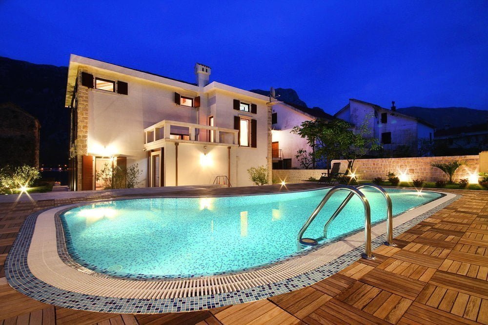 Evening villa in Prčanj, Montenegro: a private house with a pool, lighting, and a wooden-deck terrace.