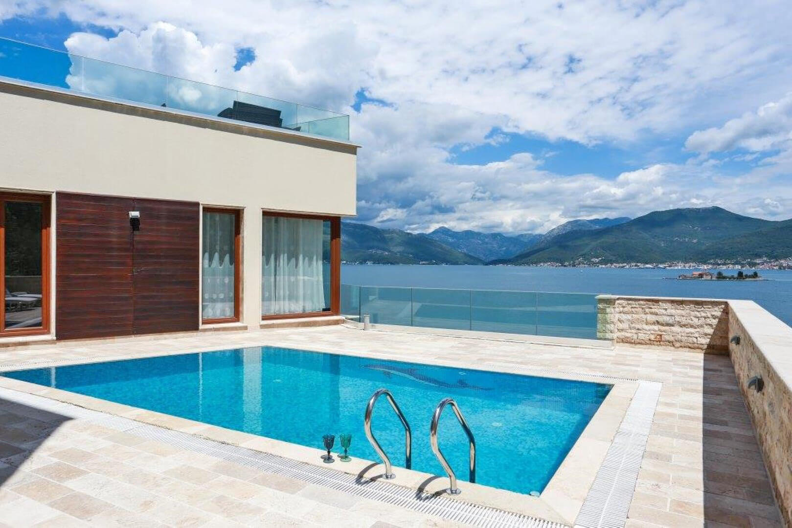 Modern villa in Krašići, Montenegro: a swimming pool with sea and mountain views, and a terrace with stone finishes.