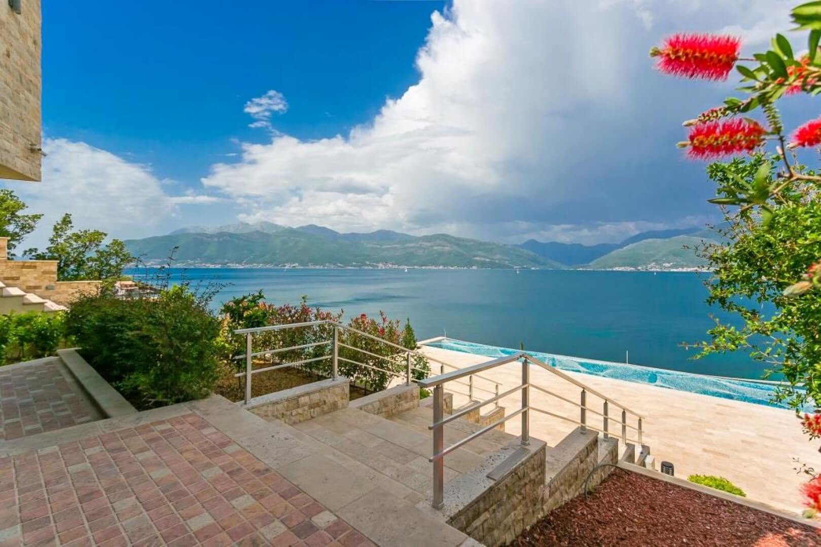 Sea and pool view from the villa terrace in Krašići, Montenegro: stone finish, staircase, and panoramic landscape.