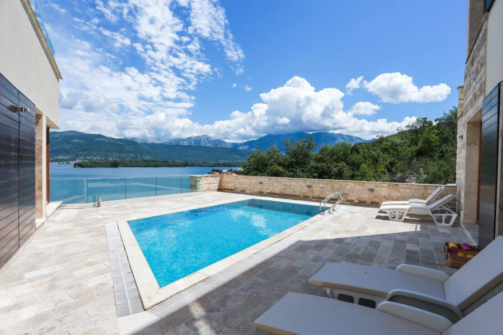 Terrace with a pool and sea view in a villa, Krašići, Montenegro: stone finish, sun loungers, and panoramic scenery.