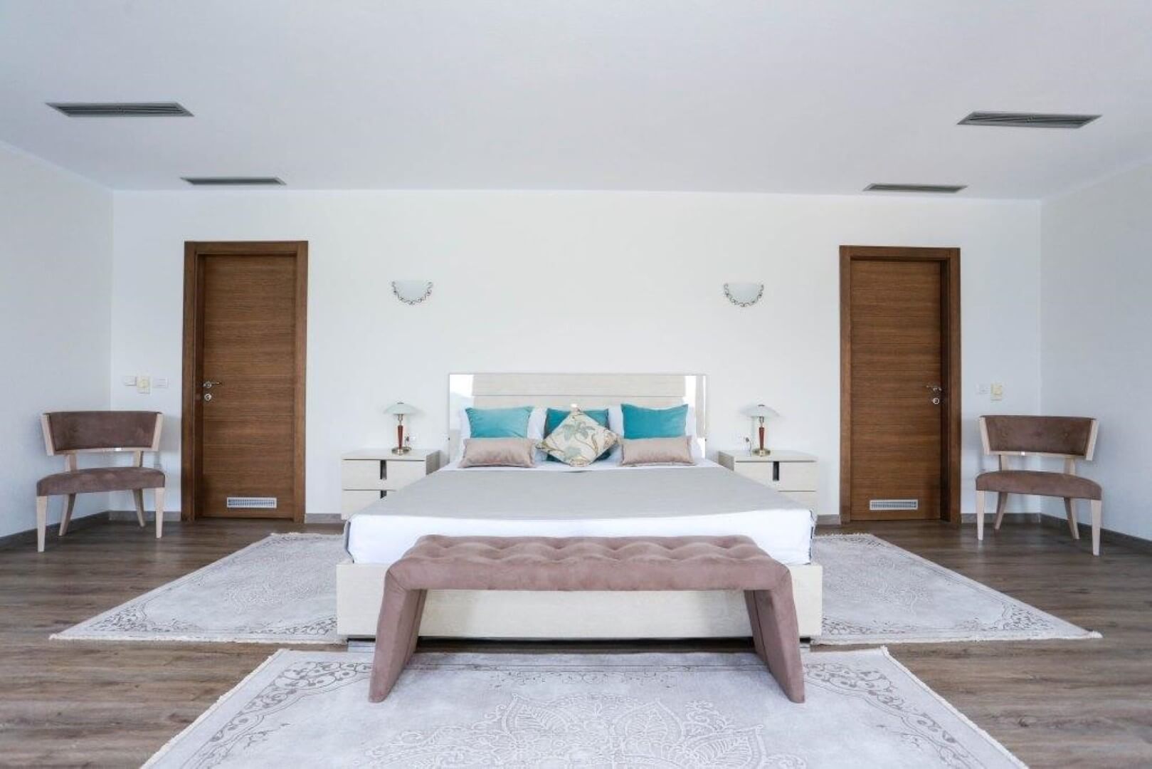 Bright bedroom with a double bed and rugs in a villa in Krašići, Montenegro: modern interior with furniture.