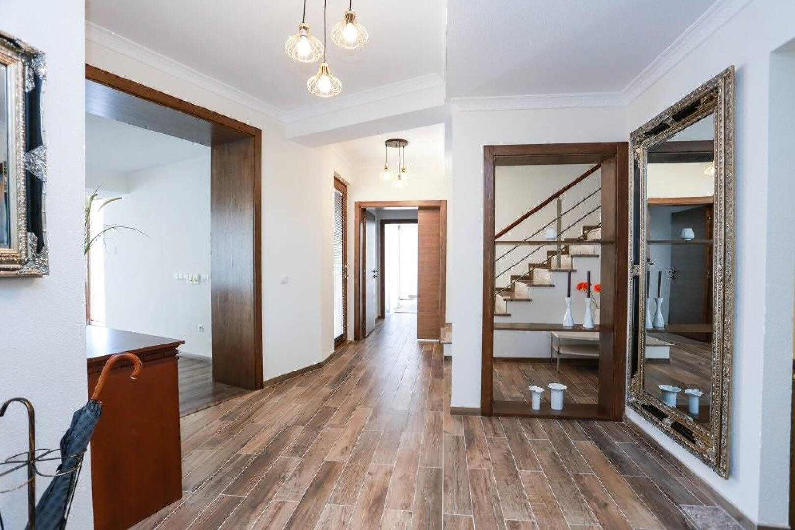 Villa hallway interior in Krašići, Montenegro: wood finishes, staircase, framed mirror, and modern lighting.