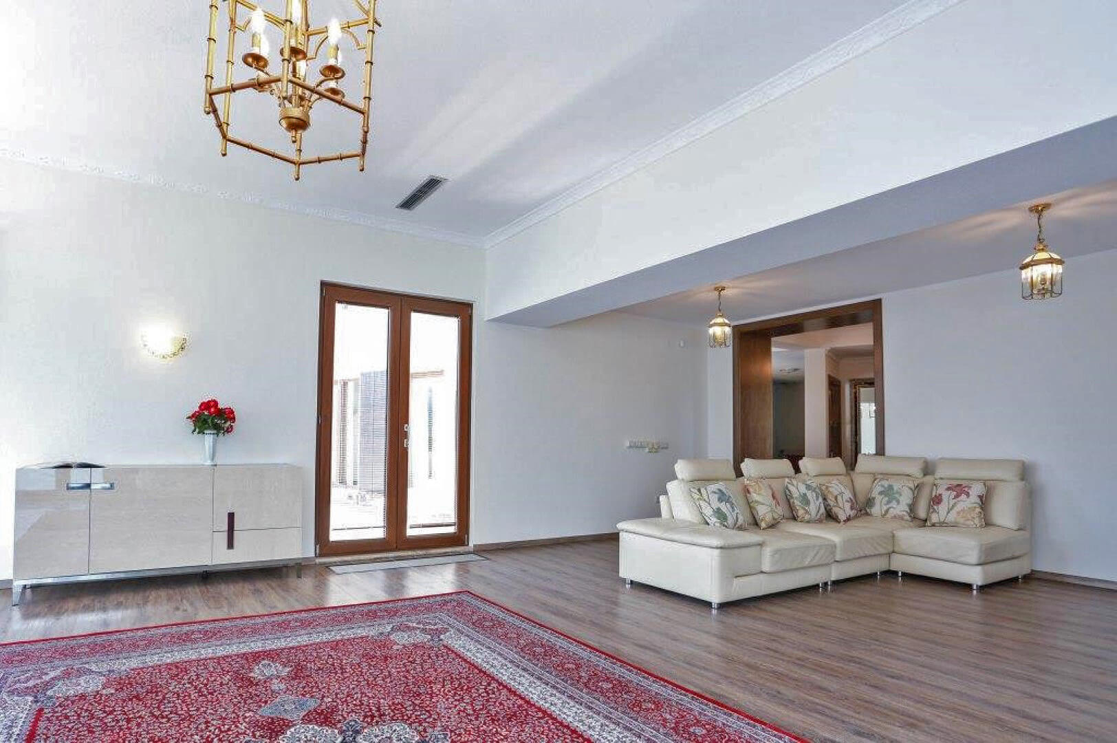 Spacious living room with a white leather sofa and classic chandeliers in a villa in Krašići, Montenegro.