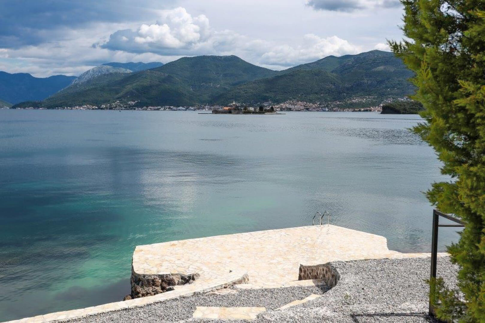Sea and mountain view from the villa’s private stone beach in the village of Krašići, Montenegro, with access to the water via stairs.