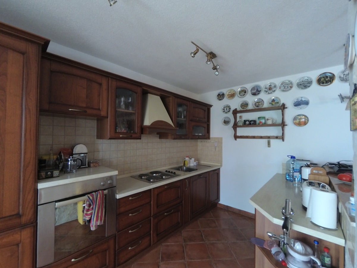 Kitchen with wooden cabinetry in a classic style in a villa in Prčanj, Montenegro: stove, oven, and wall decor.