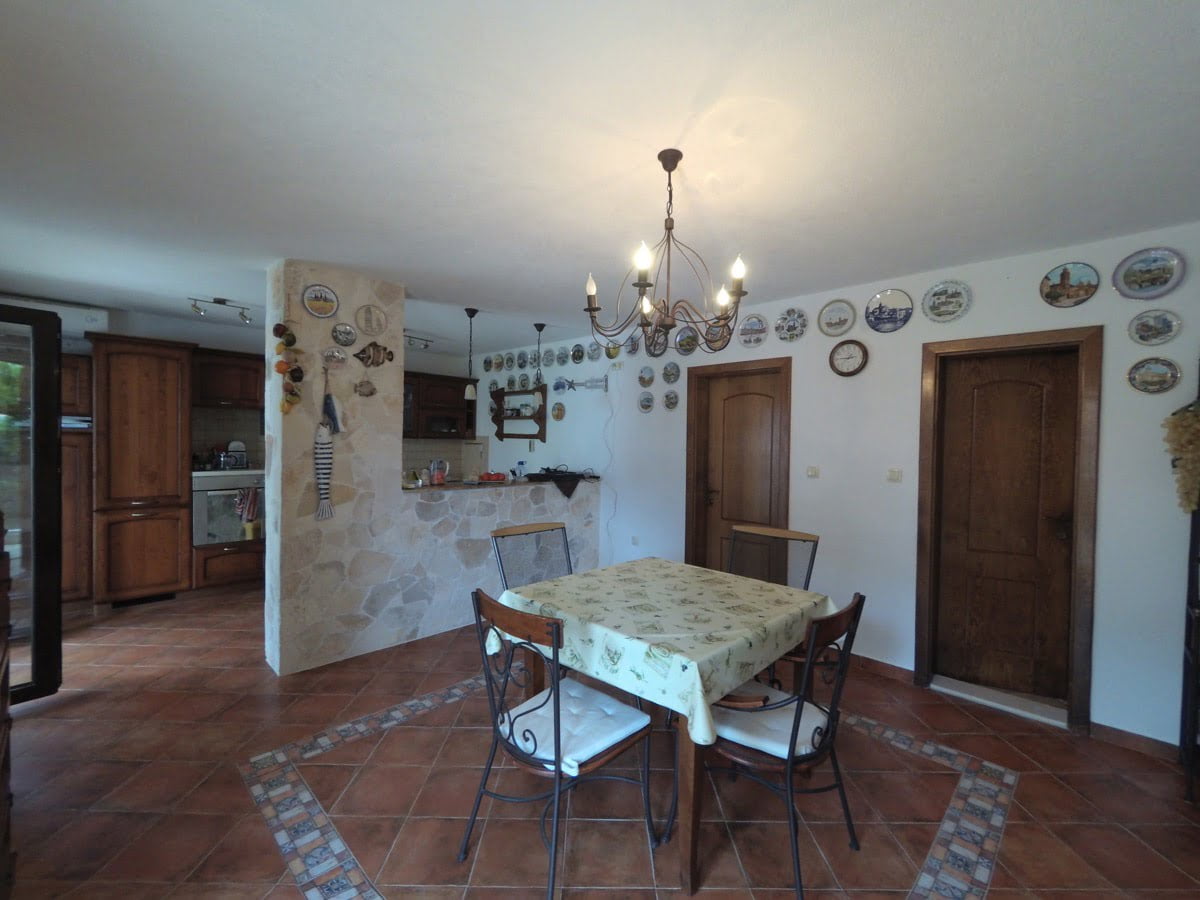Living room interior with dining area in a villa in Prčanj, Montenegro: stone finishes, wooden furniture, and decor.