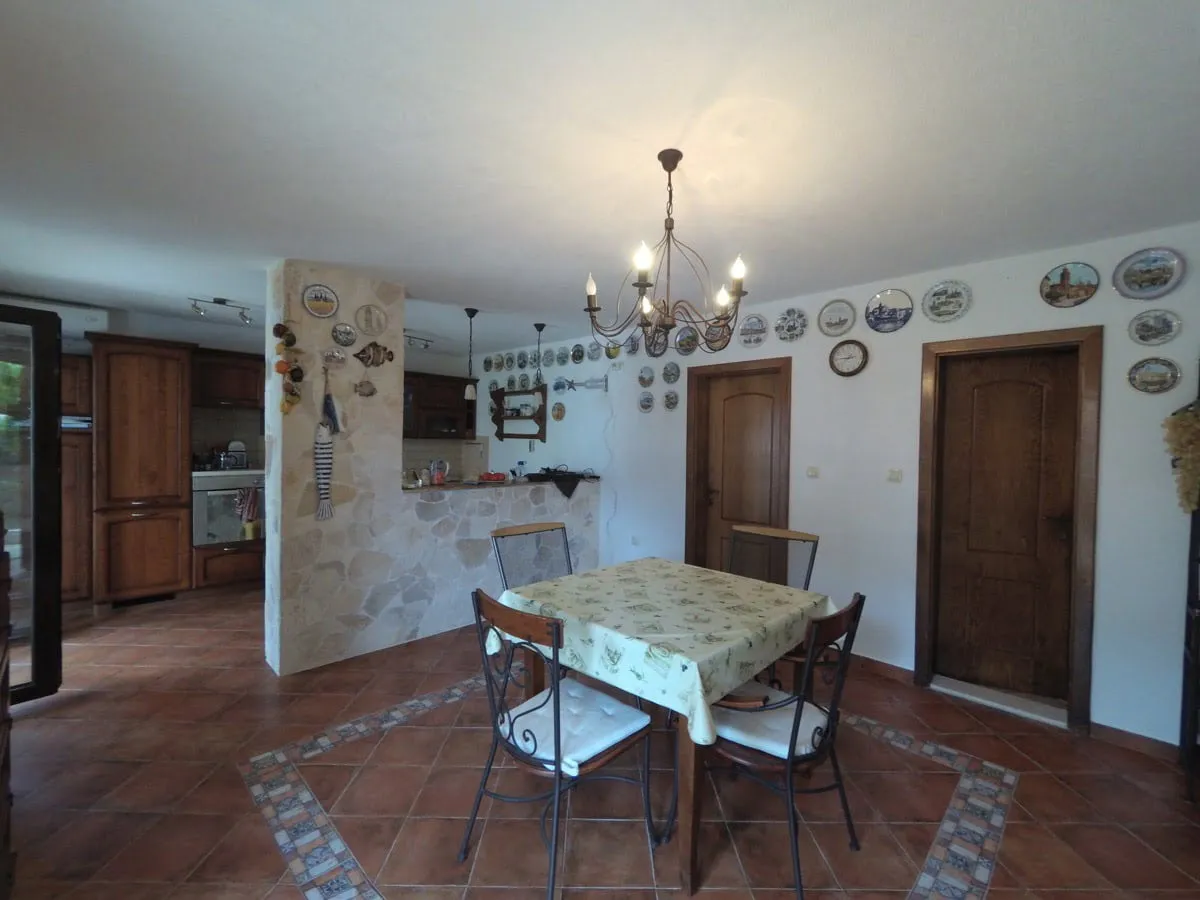Dining area with table and chairs, adjacent kitchen cabinets, stone partition, and decorative plates on walls.