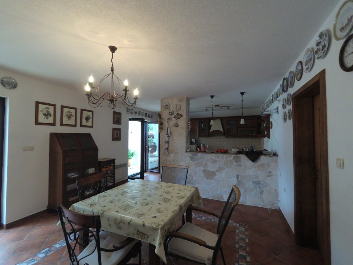 Living room with dining area and kitchen in a villa, Prčanj, Montenegro: stone finishes, wooden furniture, and access to the terrace