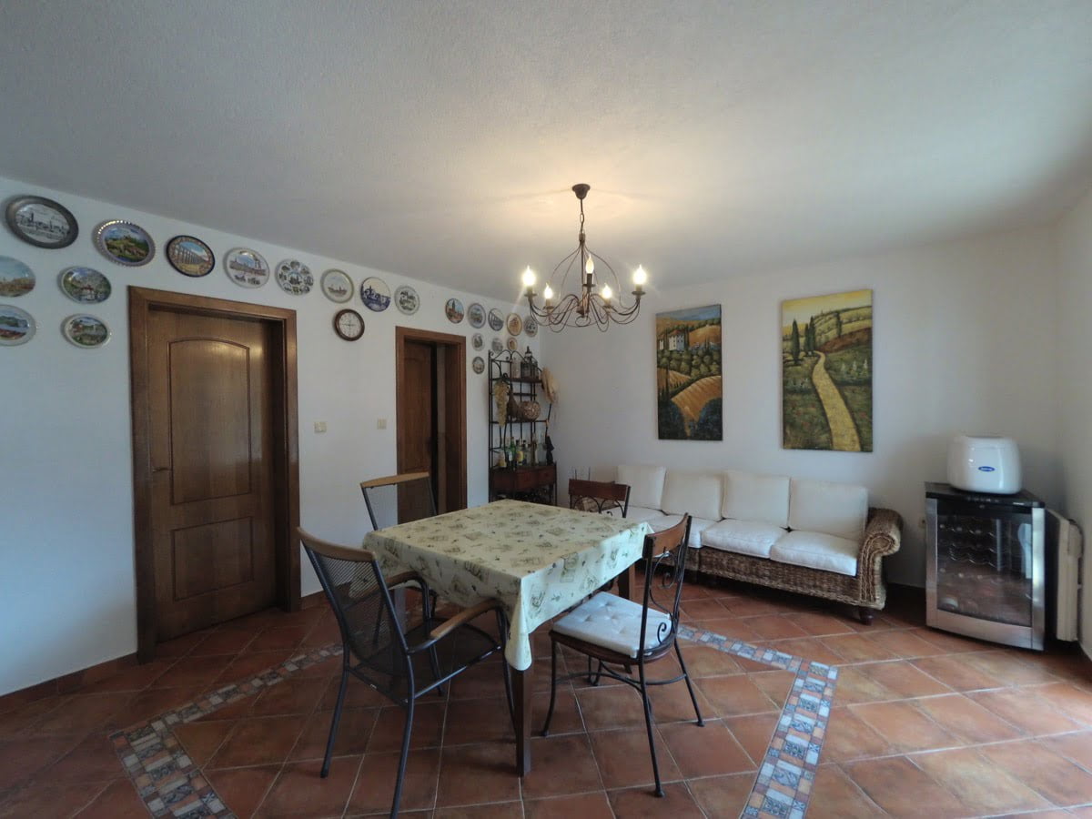 Living room with dining area in a villa in Prčanj, Montenegro: wicker sofa, wrought-iron chairs, and plate wall decor.
