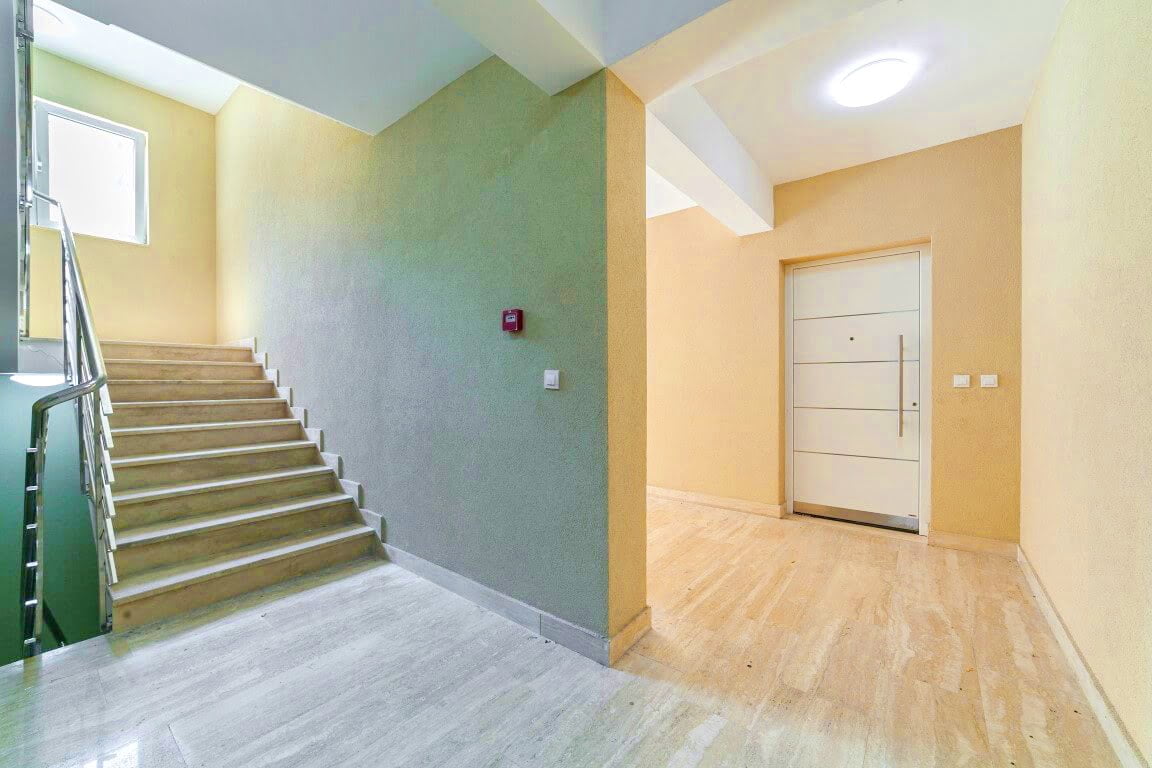 Bright entrance hall with staircase and entrance door in a residential complex, Kotor, Montenegro. Modern interior finish.