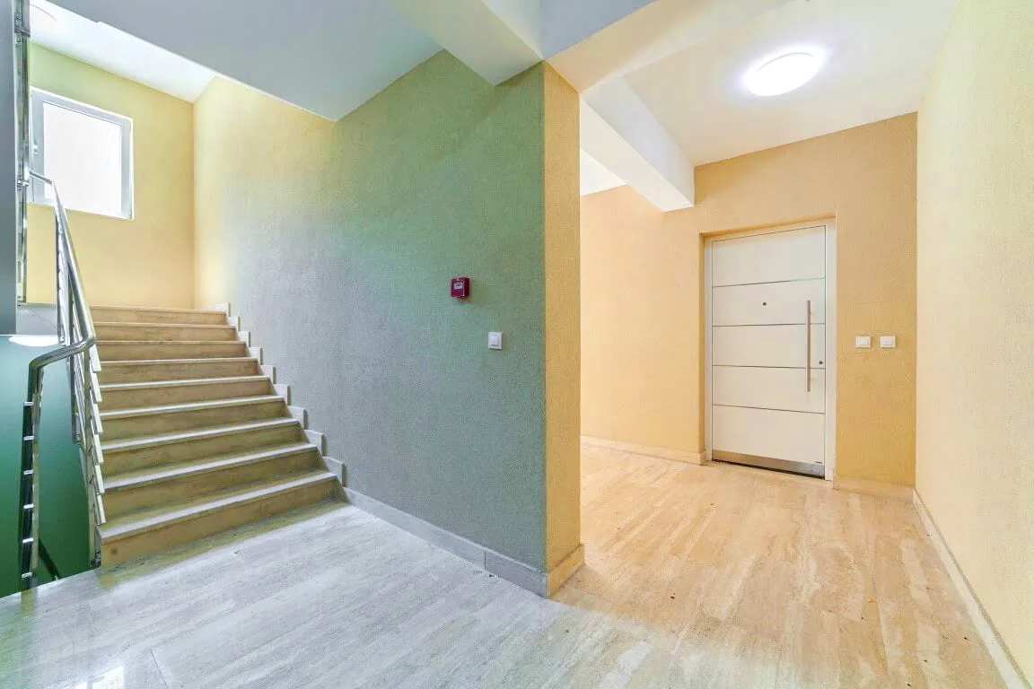 Entryway featuring a staircase with metal railing and a white door.