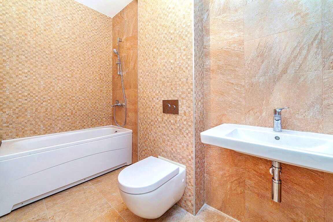 Modern bathroom with white sanitary ware and beige tiles in an apartment, Kotor, Montenegro.