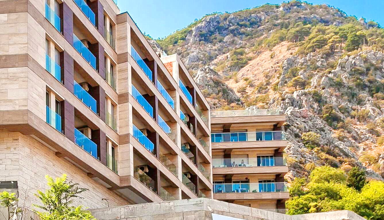Modern residential complex with terraces at the foot of the mountains in Kotor, Montenegro: view of the building facade.