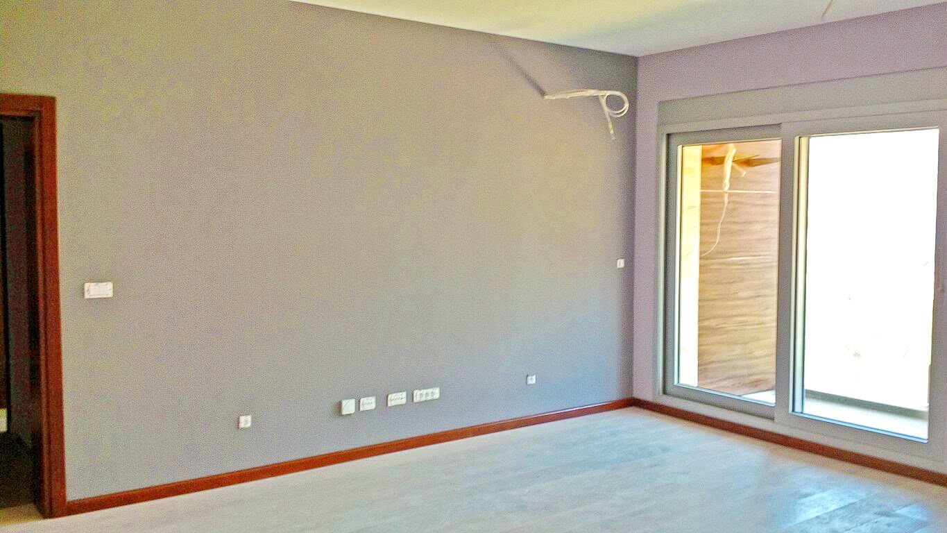 Bright living room in an apartment in Kotor, Montenegro: gray walls, panoramic window and access to the terrace, modern renovation.