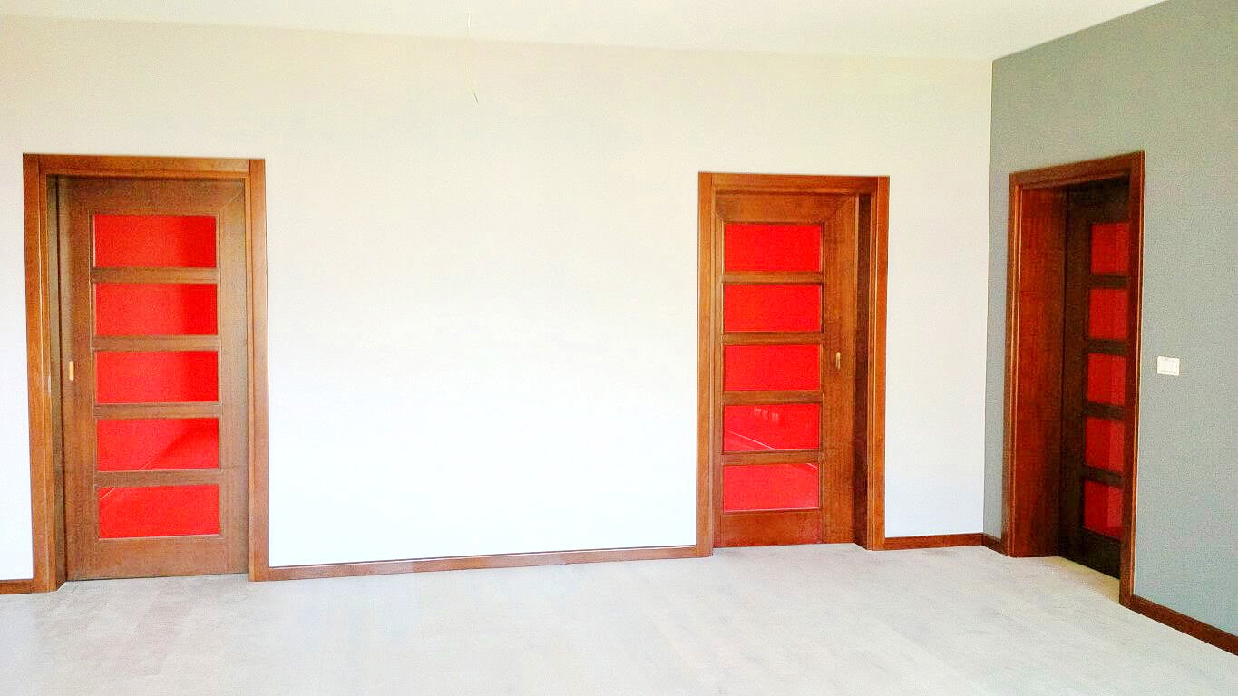 Living room interior in an apartment, Kotor, Montenegro: light walls, wooden doors with red glass inserts.